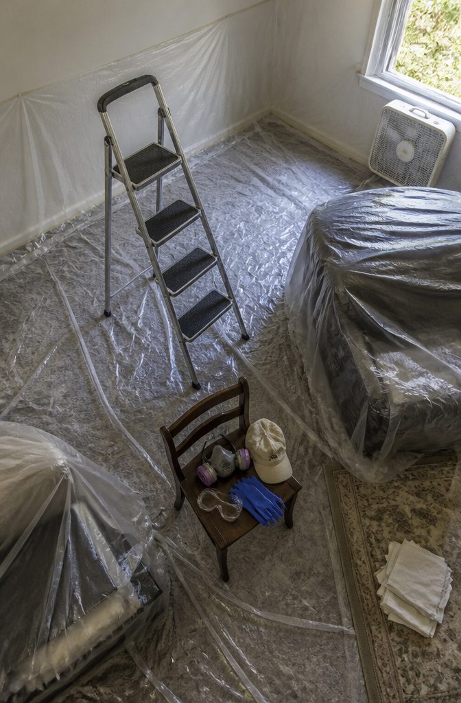 How to Clean Popcorn Walls: 6 Steps That Work 3 Room floor and furniture covered with plastic sheeting beneath a popcorn ceiling
